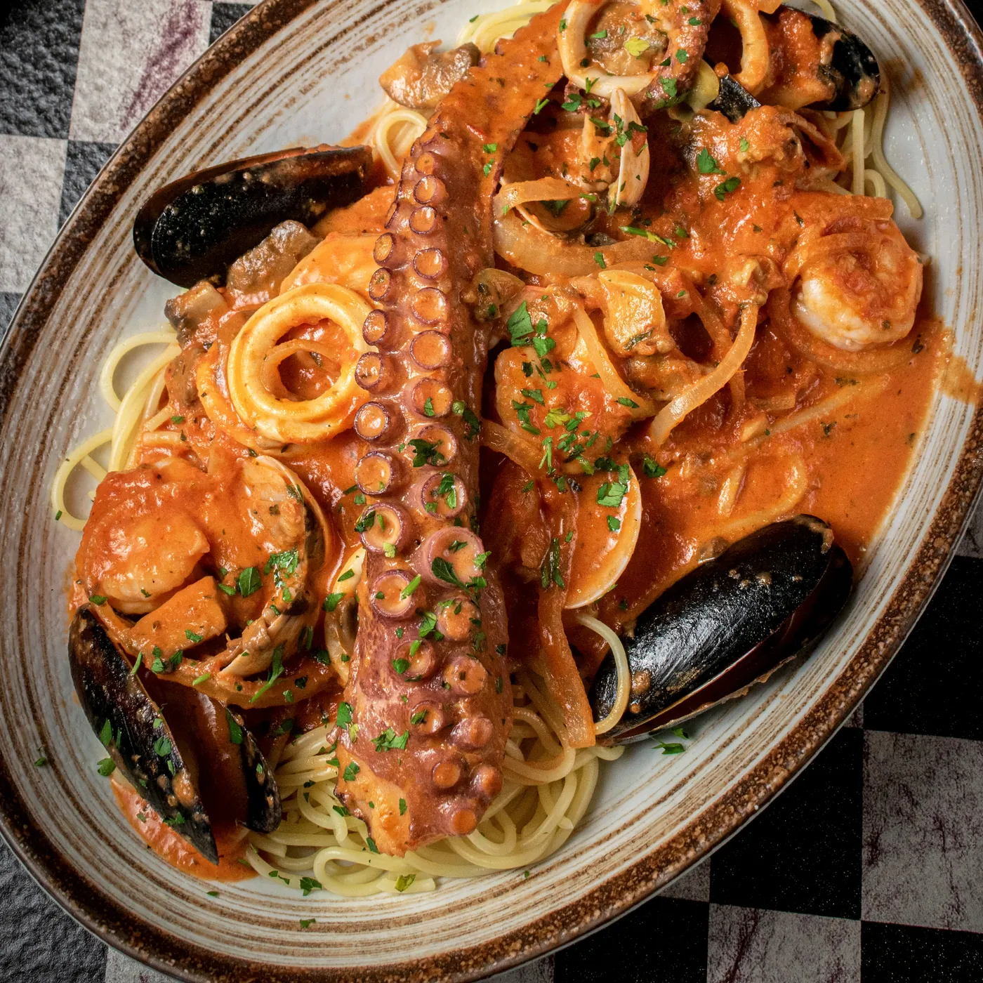 Seafood Pescatore with octopus, mussels and calamari in pink sauce over spaghetti
